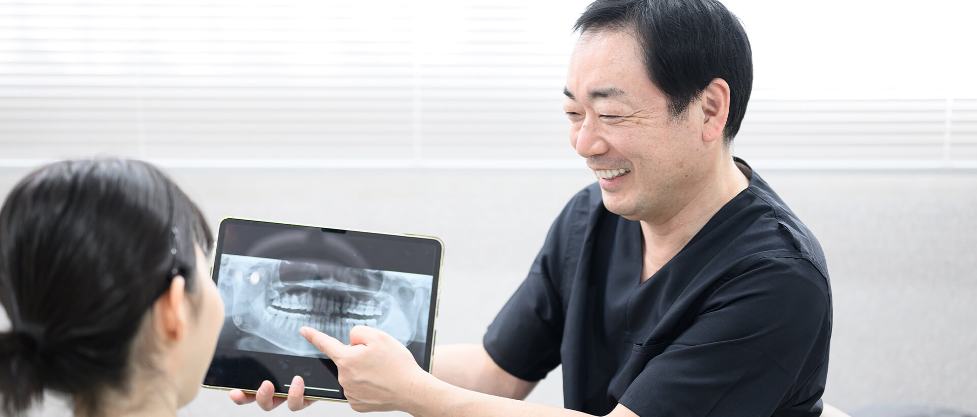 患者に歯のレントゲンを見せる歯科医
